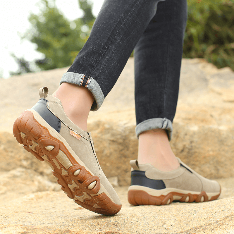 Man wearing non-slip hiking shoes SF1156 on rocky terrain, showcasing lightweight design and superior grip for outdoor trekking.